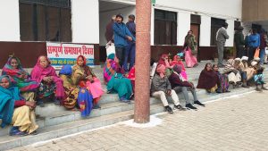 जिला अधिकारी के इंतजार में बैठे ग्रामीण